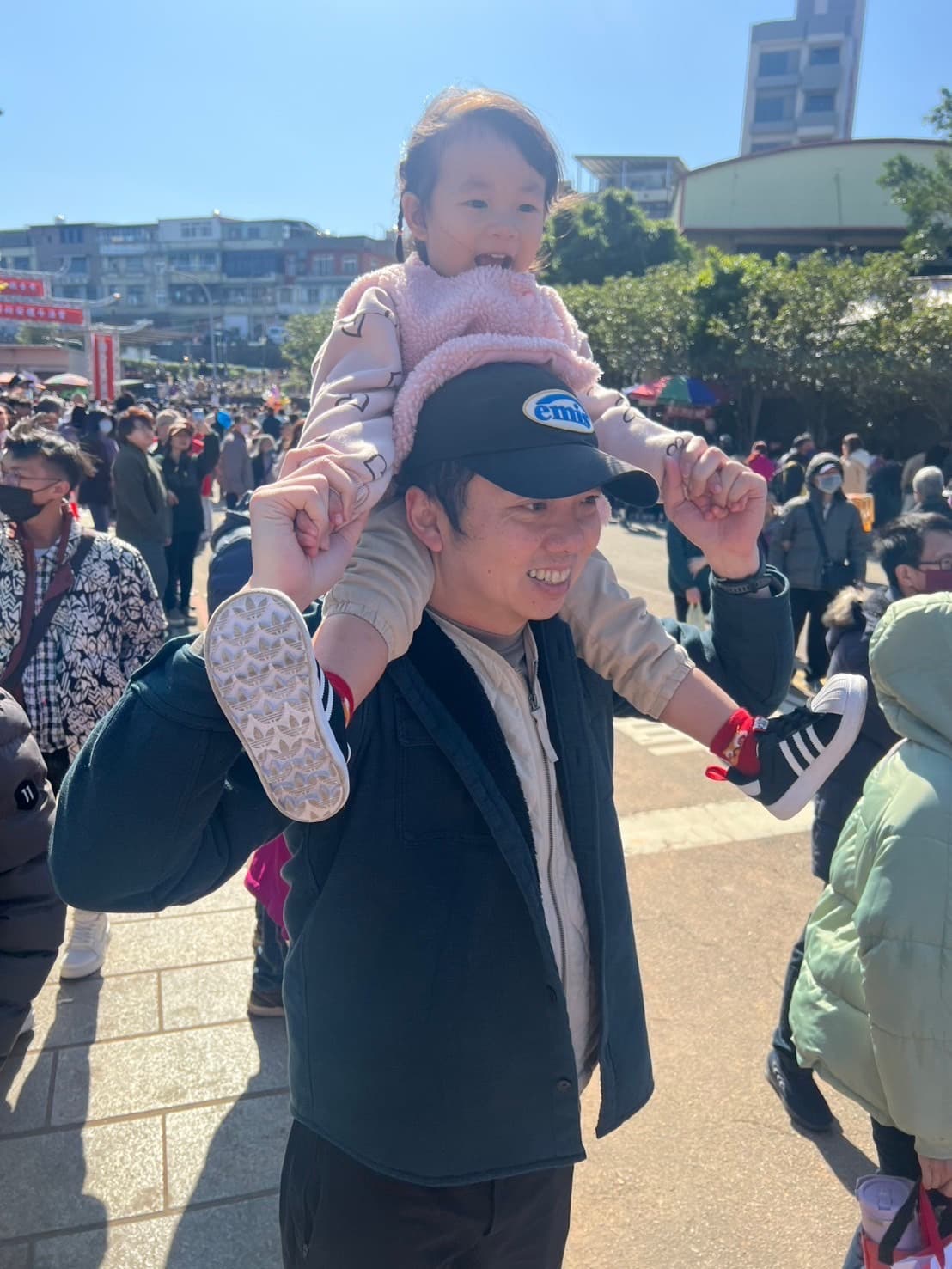 Dad carrying daughter on shoulders, both smiling happily